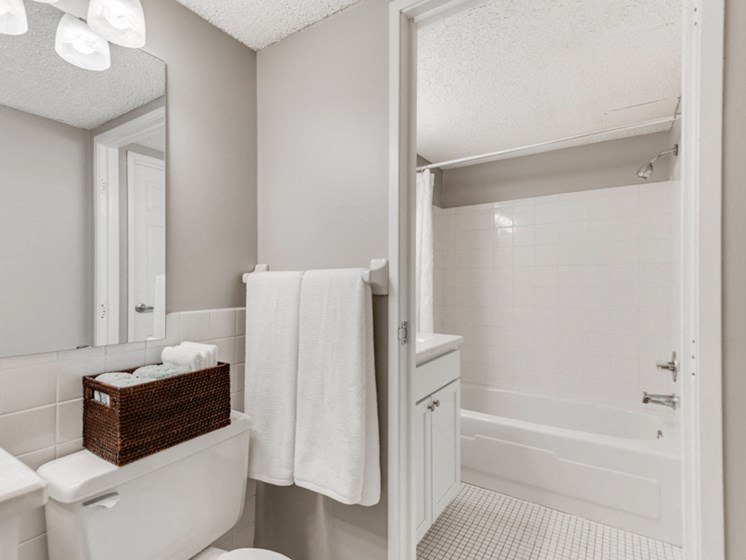 White bathroom with bright lights and the camera facing the bathtub and shower